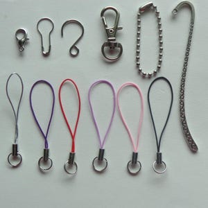 May include: An assortment of silver-toned metal hardware and colorful lanyards. The hardware includes a lobster clasp, key ring, and a chain. The lanyards are in purple, red, light purple, pink, and black.