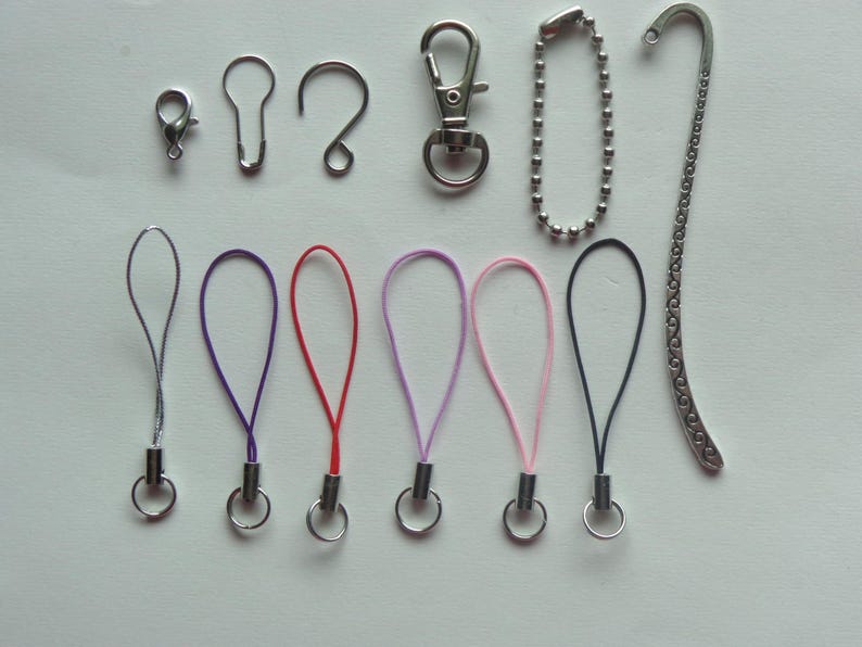 May include: An assortment of silver-toned metal hardware and colorful lanyards. The hardware includes a lobster clasp, key ring, and a chain. The lanyards are in purple, red, light purple, pink, and black.