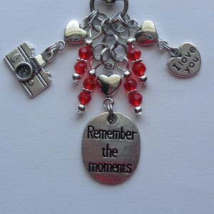 May include: Silver charm bracelet with red beads, a camera charm, heart charms, and a charm that says "Remember the moments".
