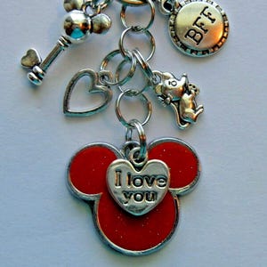 May include: Silver-toned keychain with multiple charms. Charms include a key, heart, mouse, and a round charm with "BFF" engraved. The main charm is a red Mickey Mouse head with a heart that says "I love you".