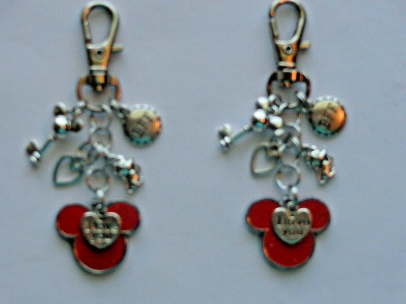 May include: Two keychains with silver-tone charms and red Mickey Mouse-shaped pendants. Each keychain has a lobster clasp, charms, and a heart-shaped pendant with the words "I love you."