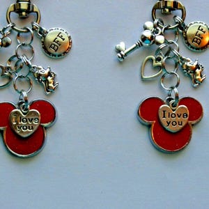 May include: Two matching keychains with silver charms and red Mickey Mouse head pendants. Each keychain has a key, heart, and a charm that says "BFF". The Mickey Mouse pendants have a heart that says "I love you".