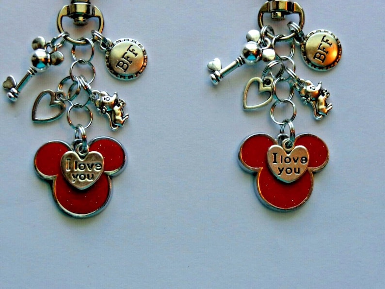May include: Two matching keychains with silver charms and red Mickey Mouse head pendants. Each keychain has a key, heart, and a charm that says "BFF". The Mickey Mouse pendants have a heart that says "I love you".