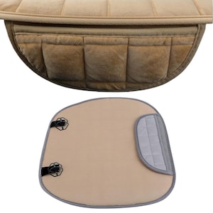 May include: A beige car seat cushion with a grey strap and two black clips. The cushion is made of a soft, plush material and has a quilted design.