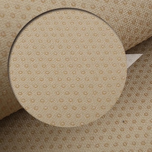 May include: Close-up of a beige fabric with a textured pattern of small, evenly spaced dots.
