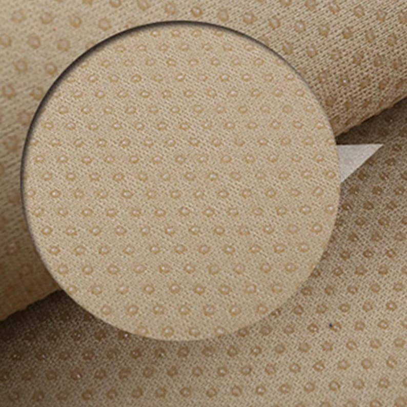 May include: Close-up of a beige fabric with a textured pattern of small, evenly spaced dots.