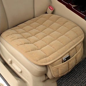 May include: A tan quilted car seat cushion with a zipped pocket on the side. The cushion is made of a soft, plush fabric and is designed to provide comfort and support.