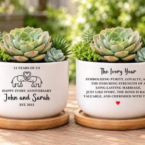 May include: Two white ceramic planters on bamboo saucers, each holding a green succulent. The left planter features two elephants, the text 14 YEARS OF US, HAPPY IVORY ANNIVERSARY, John and Sarah, and EST. 2012. The right planter displays The Ivory Year text.