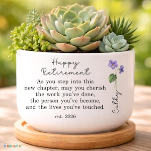 May include: A white ceramic planter with a succulent arrangement. The planter has the text "Happy Retirement" and a personalized name. The succulent arrangement includes various green succulents and a wooden saucer.