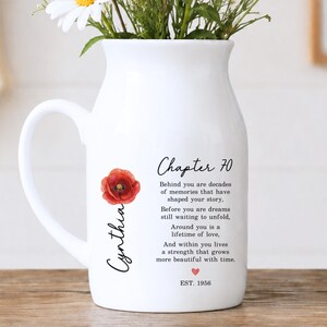 May include: A white ceramic pitcher featuring a red poppy flower illustration, the name Cynthia in black script, and the text Chapter 70, followed by a sentimental poem about memories and love, with a small red heart and the text EST. 1956.