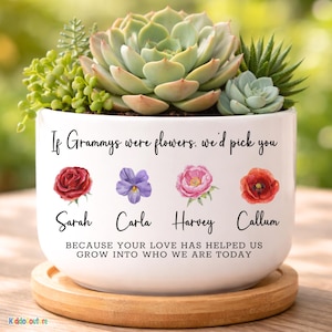 May include: White ceramic planter with a variety of succulents. The planter has the text "If Grammys were flowers, we'd pick you" and the names Sarah, Carla, Harvey, and Callum. A wooden saucer is beneath the planter.