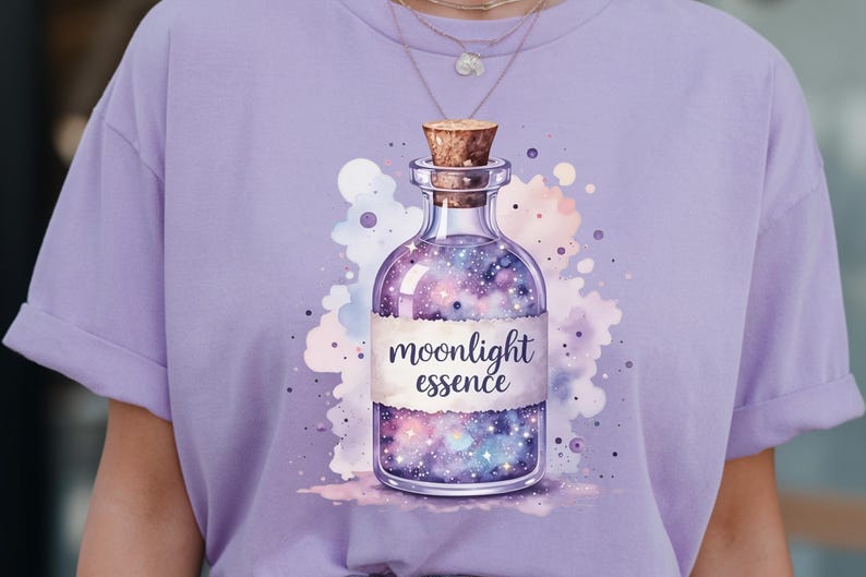 May include: A light purple t-shirt featuring a watercolor illustration of a glass bottle with a cork stopper. The bottle is filled with a galaxy design and the words "moonlight essence" are printed on a label.