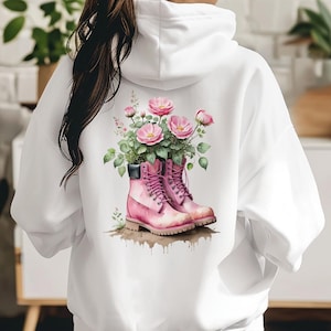 May include: White hoodie with a pink floral design featuring pink boots with laces. The flowers are growing out of the boots.