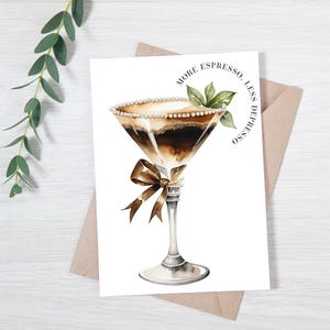 May include: A white card with a watercolor illustration of a martini glass filled with espresso and topped with whipped cream and a pearl border. The text "More Espresso, Less Depresso" is written in a circle around the glass.