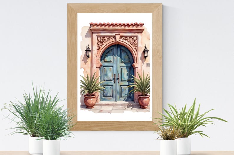 May include: Watercolor painting of a teal arched door with a detailed stone frame, flanked by two lanterns. The door is set in a peach-colored wall, and the artwork is framed in a light wood frame. Potted plants are in front of the artwork.