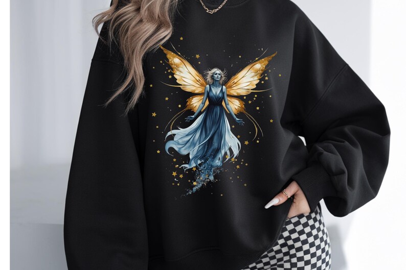 Op de afbeelding: Zwart sweatshirt met een aquarel illustratie van een fee met gouden vleugels en een vloeiende blauwe jurk. Het ontwerp bevat gouden sterren en een hemels thema, wat een grillige esthetiek cre&euml;ert.