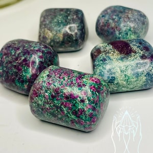 May include: Five tumbled stones of green ruby zoisite, a green gemstone with red ruby inclusions. The stones are smooth and polished, with a variety of shapes and sizes.