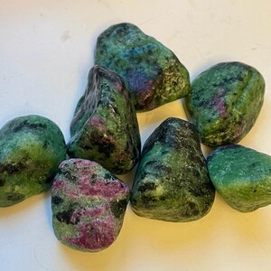Puede incluir: Una colección de siete piedras pulidas de color verde y rosa. Las piedras tienen un aspecto moteado con tonos de verde, rosa y negro.