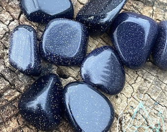 Puede incluir: Una colección de piedras de arenisca azul pulidas con un acabado brillante y brillante. Las piedras son lisas y pulidas, y tienen una variedad de formas y tamaños.