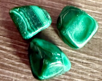 May include: Three green malachite stones with swirling patterns. The stones are smooth and polished.