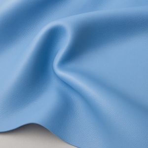 May include: A close-up shot of a light blue leather material with a textured surface. The fabric is folded and draped, creating soft shadows and highlights. The color is a vibrant, solid light blue.