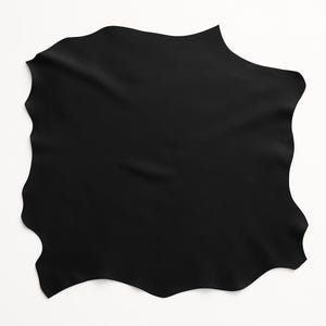 May include: A large, irregularly shaped piece of black leather. The material has a smooth, matte finish with subtle variations in texture. The edges are uneven, giving it a natural, organic appearance. The leather is likely suitable for crafting.