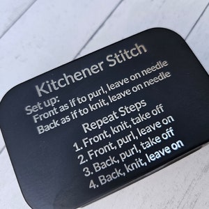 May include: A black rectangular card with the text "Kitchener Stitch" and instructions for knitting the stitch. The instructions include "Set up: Front as if to purl, leave on needle. Back as if to knit, leave on needle. Repeat Steps: 1. Front, knit, take off. 2. Front, purl, leave on. 3. Back, purl, take off. 4. Back, knit, leave on."