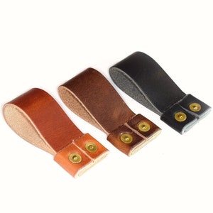 May include: Three leather straps with brass rivets. The straps are brown, dark brown, and black.