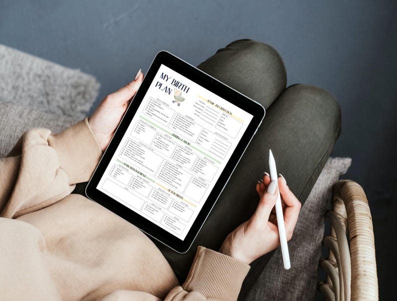 May include: A digital tablet displaying a birth plan template titled "MY BIRTH PLAN". The template includes sections for personal information, labor and delivery preferences, and newborn care. A white stylus is held in the hand, ready to make notes on the tablet.