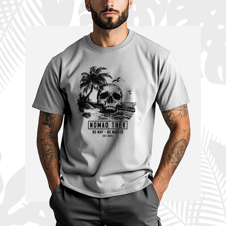 K&ouml;nnte beinhalten: Hellgraues T-Shirt mit einem schwarz-wei&szlig;en Grafikdesign eines Sch&auml;dels an einem Strand mit Palmen. Das Shirt tr&auml;gt den Text "NOMAD TREK" und "NO MAP - NO MASTER - EST 2025".