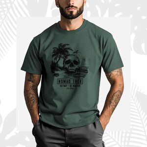 K&ouml;nnte beinhalten: Gr&uuml;nes T-Shirt mit einer schwarzen Grafik eines Sch&auml;dels an einem Strand mit Palmen und dem Text "NOMAD TREK - NO MAP - NO MASTER - EST 2025". Das Shirt hat kurze &Auml;rmel und einen Rundhalsausschnitt.