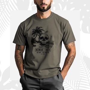 K&ouml;nnte beinhalten: Olivgr&uuml;nes T-Shirt mit einer schwarzen Grafik eines Sch&auml;dels an einem Strand mit Palmen und dem Text "NOMAD TREK". Das Shirt enth&auml;lt auch die S&auml;tze "NO MAP - NO MASTER" und "EST 2025".