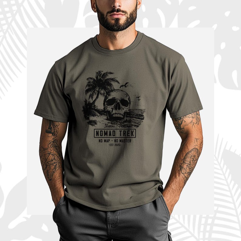K&ouml;nnte beinhalten: Olivgr&uuml;nes T-Shirt mit einer schwarzen Grafik eines Sch&auml;dels an einem Strand mit Palmen und dem Text "NOMAD TREK". Das Shirt enth&auml;lt auch die S&auml;tze "NO MAP - NO MASTER" und "EST 2025".