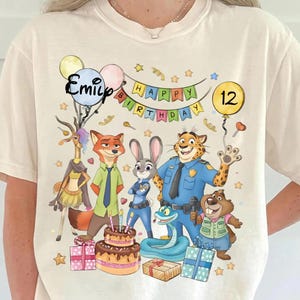 K&ouml;nnte beinhalten: Eine wei&szlig;e Keramik-Tasse mit schwarzem Henkel und dem Text "But First, Coffee" in fetter, schwarzer Schrift. Die Tasse steht vor einem verschwommenen Hintergrund, der eine gem&uuml;tliche Umgebung suggeriert.