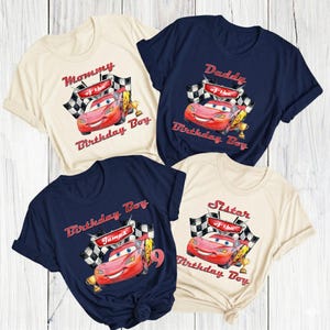 May include: Four t-shirts with a cartoon car design. The shirts are in cream and navy blue. Each shirt has text that says "Mommy of the Birthday Boy", "Daddy of the Birthday Boy", "Birthday Boy", and "Sister of the Birthday Boy".