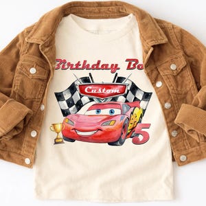 May include: A white ceramic mug with a black handle and the text "But First, Coffee" in a bold, black font. The mug is sitting on a wooden surface. The mug appears to be empty.