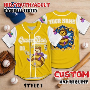 Puede incluir: Camiseta de b&eacute;isbol amarilla con mangas blancas, con un dise&ntilde;o de abeja reina de dibujos animados. La camiseta tiene el texto "Queen Bee" y "00" en la parte delantera. La parte trasera de la camiseta tiene un gr&aacute;fico de abeja y el texto "YOUR NAME".