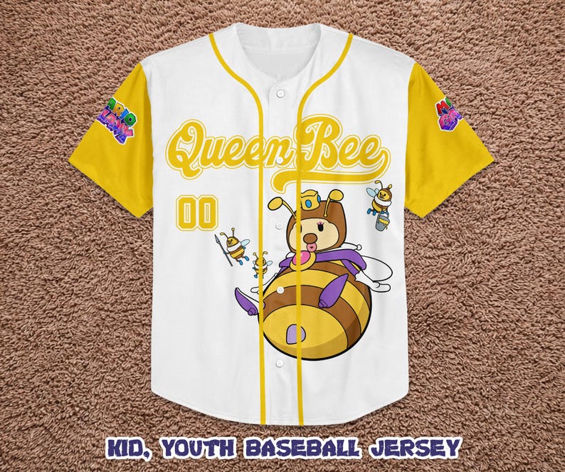 Puede incluir: Camiseta de b&eacute;isbol blanca y amarilla con un dise&ntilde;o de abeja reina de dibujos animados. La camiseta tiene mangas y ribetes amarillos, con las palabras "Queen Bee" en letras doradas. El n&uacute;mero "00" est&aacute; en la parte delantera. La camiseta est&aacute; etiquetada como "Kid, Youth Baseball Jersey".