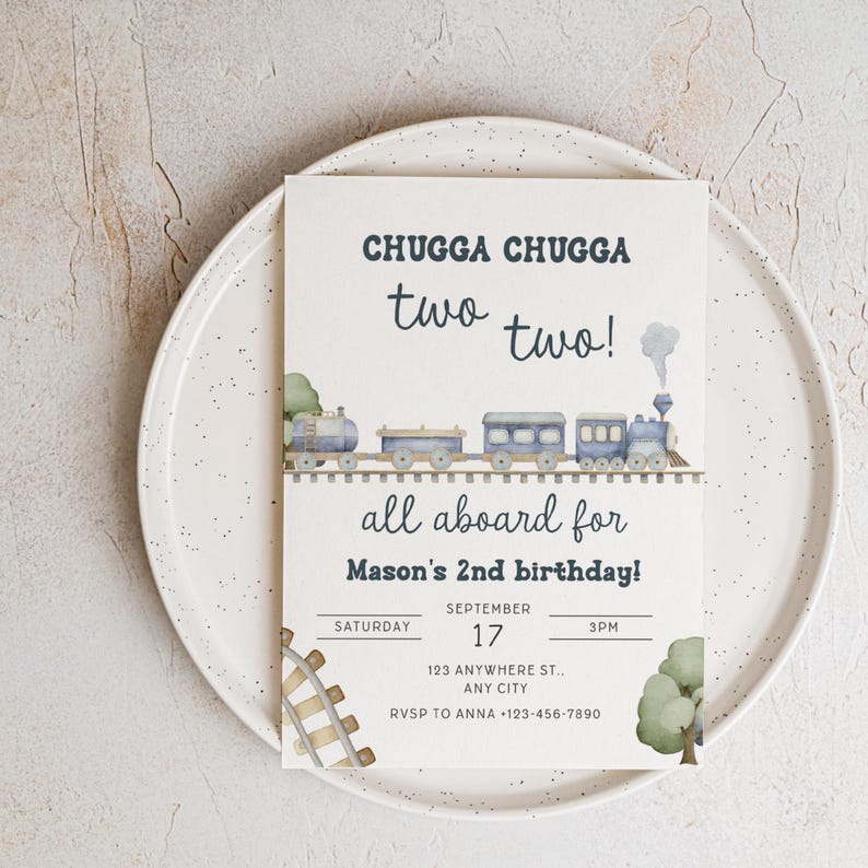 May include: A birthday invitation with a train theme. The invitation reads "CHUGGA CHUGGA two two!" and "all aboard for Mason's 2nd birthday!" Includes date, time, and RSVP information. The invitation is on a white plate.