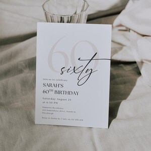 May include: A white invitation card with the text "60 sixty" in a stylish font, announcing Sarah's 60th birthday celebration. The card includes the date, time, and location details, with a clear and elegant design.