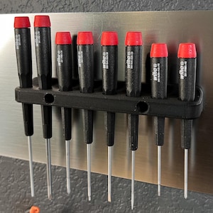 May include: A set of eight screwdrivers with red handles and black shafts are mounted on a black magnetic holder. The screwdrivers are labeled "Wera" and have different sizes.