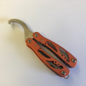 May include: A multi-tool with a hook, pliers, and other tools. The tool is orange and silver and has a textured surface.