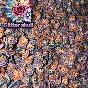 May include: A large collection of small, circular polymer clay slices featuring cartoon-style faces with various hair colors including orange, purple, and dark blue. In the upper left corner, a graphic shows a skull with a floral headdress and the text Glitter skull.
