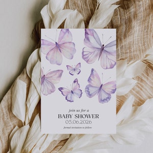May include: A white card with a purple watercolor butterfly design. The text on the card reads "join us for a BABY SHOWER 05.06.2026 formal invitation to follow"