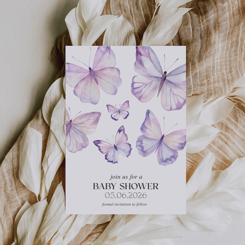 May include: A white card with a purple watercolor butterfly design. The text on the card reads "join us for a BABY SHOWER 05.06.2026 formal invitation to follow"