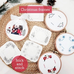 May include: A collection of circular wooden embroidery hoops and square fabric patches featuring Christmas-themed designs including snowmen, snowflakes, poinsettias, and string lights. One hoop displays a family photograph with a white ribbon bow.