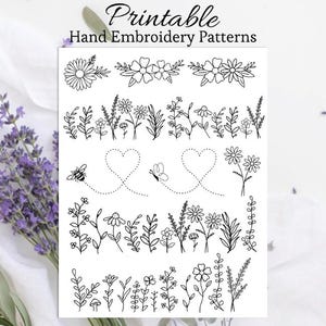 May include: A white sheet with black line art of floral embroidery patterns. The sheet includes various designs of flowers, leaves, bees, and hearts. The text "Printable Hand Embroidery Patterns" is at the top.
