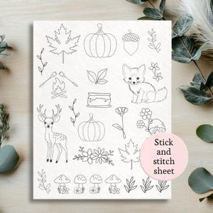 May include: A white stick and stitch sheet featuring line art illustrations of autumn-themed elements. Includes a deer, fox, pumpkins, leaves, flowers, mushrooms, and the text "Stick and stitch sheet" on a pink circle.