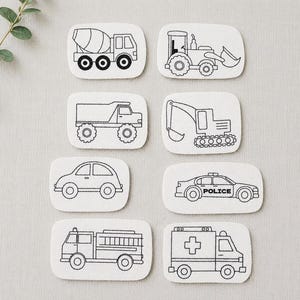Puede incluir: Ocho parches rectangulares de tela blanca con contornos bordados en negro de varios vehículos, incluyendo una hormigonera, tractor, camión volquete, excavadora, coche, coche de policía con la palabra POLICE, camión de bomberos y ambulancia con cruz.