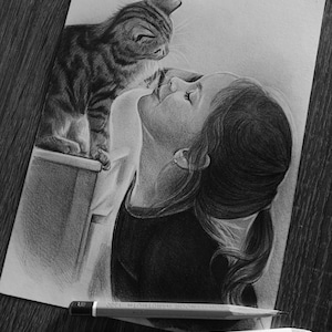 May include: A graphite pencil drawing on paper depicting a person with their hair in a ponytail looking at a tabby cat. The cat is perched on a ledge. Two Koh-I-Noor Hardtmuth pencils and a white eraser are positioned below the drawing.